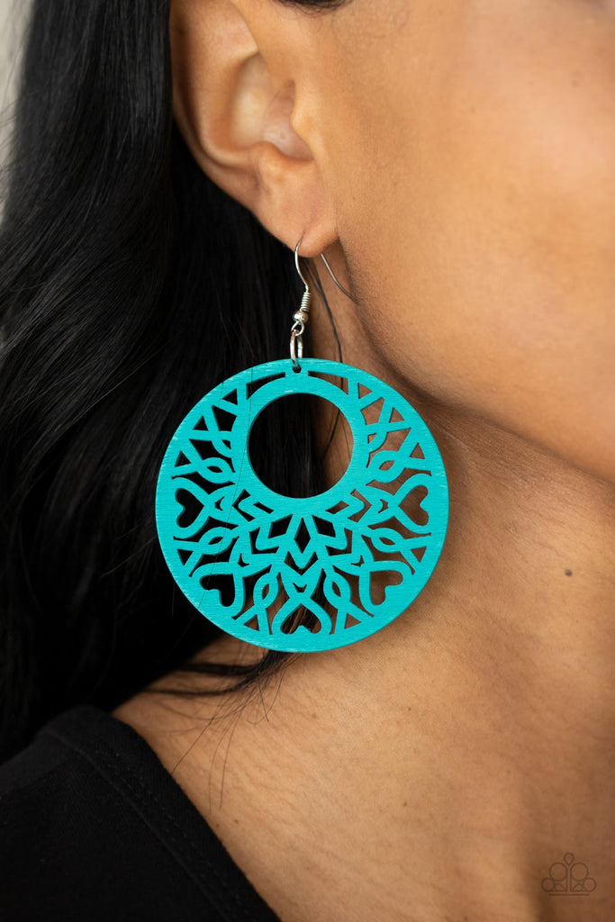 Painted in a refreshing blue, an airy circular wooden frame features a cut-out heart motif reminiscent of bohemian designs creating a free-spirited allure. Earring attaches to a standard fishhook fitting.  Sold as one pair of earrings.  