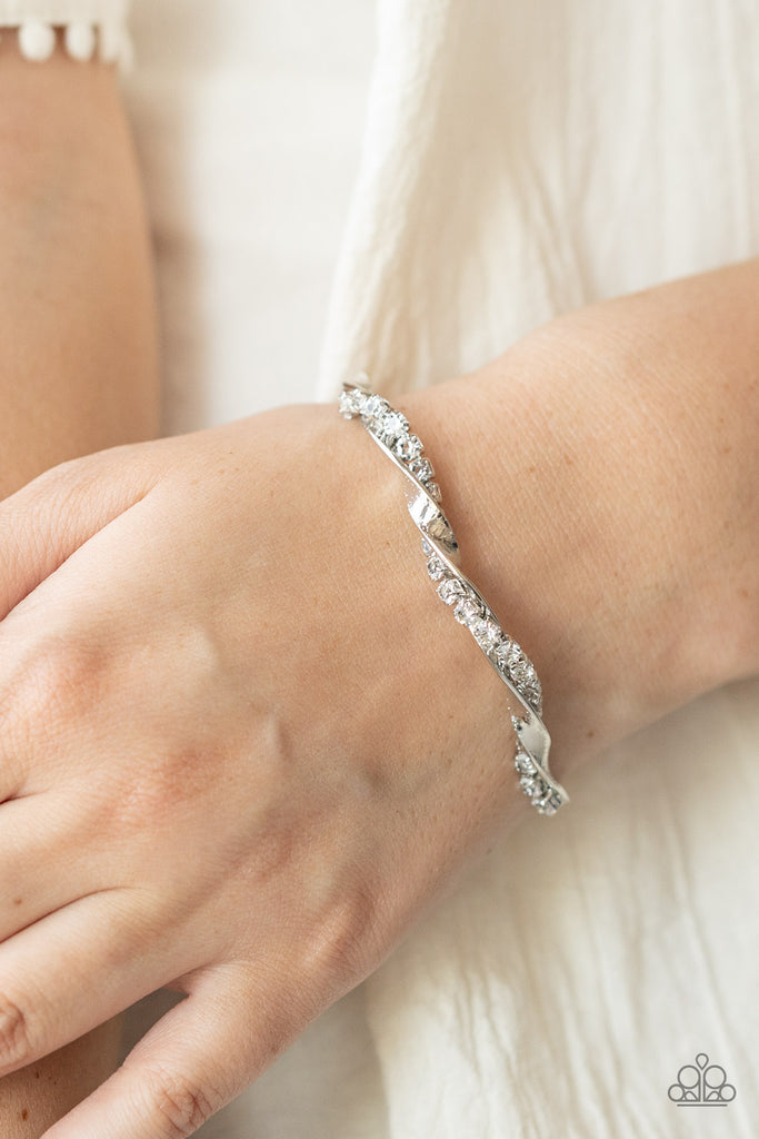 A glittery strand of glassy white rhinestones twists with a shiny silver bar around the wrist, creating a dainty cuff.  Sold as one individual bracelet.