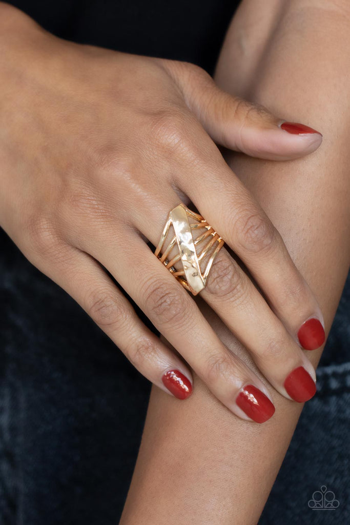 A daring hammered gold column slants across the finger intersecting an airy layered band resulting in a dramatically edgy vibe. Features a stretchy band for a flexible fit.  Sold as one individual ring.