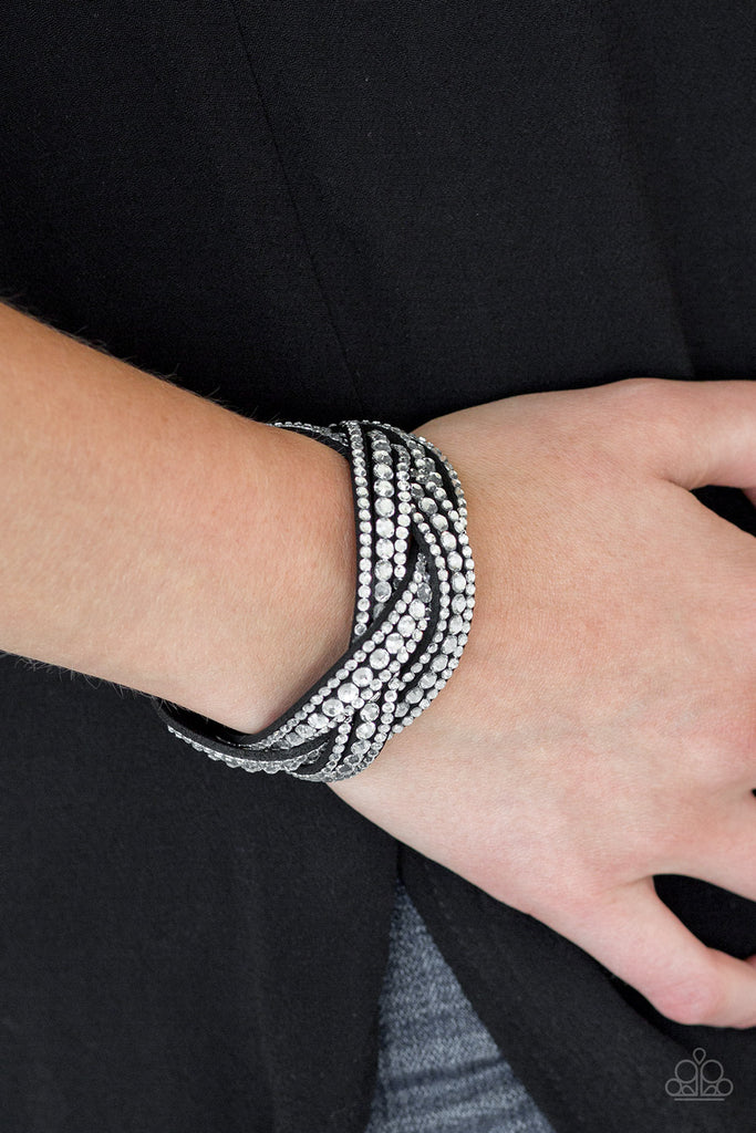 Varying in size, glassy white rhinestones are encrusted along interwoven black suede bands, creating blinding shimmer across the wrist. Features an adjustable snap closure.  Sold as one individual bracelet.