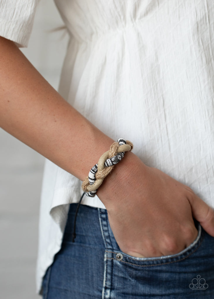 Mismatched strands of suede, twine, and black and white threaded bands delicately weave across the wrist for an earthy braided look. Features an adjustable sliding knot closure.  Sold as one individual bracelet.