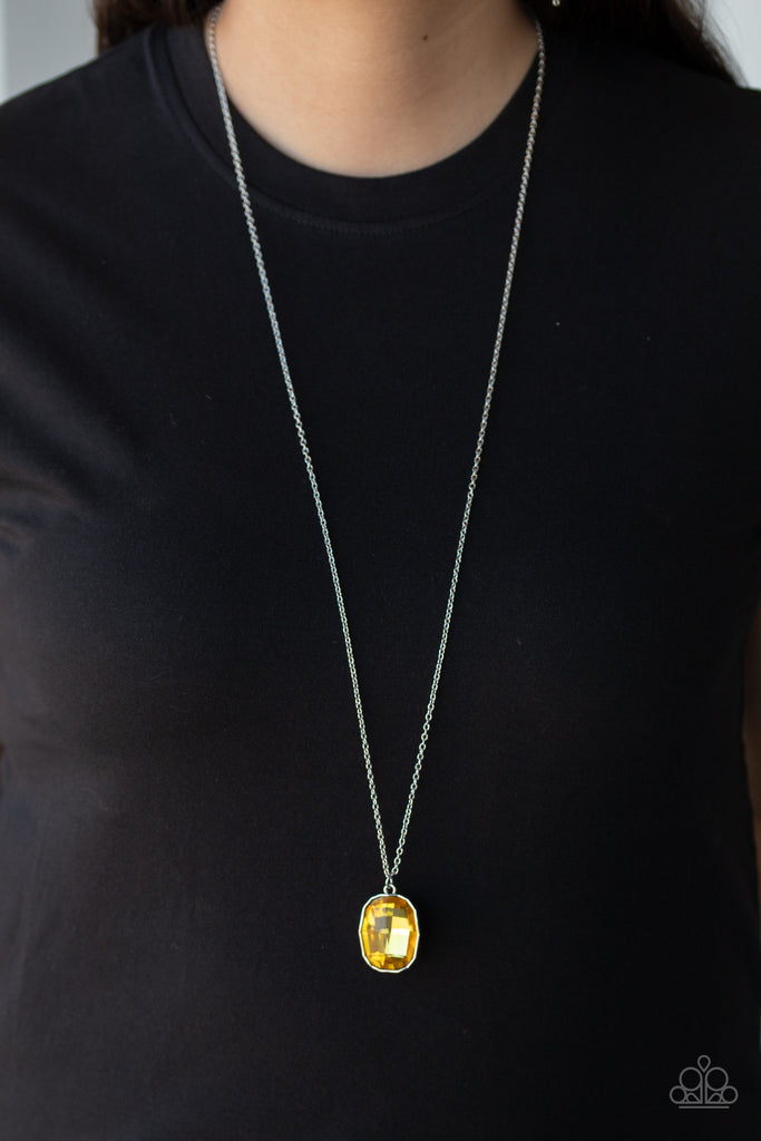 An imperfect yellow gem is pressed into the center of an edgy silver frame at the bottom of a lengthened silver chain for a glitzy look. Features an adjustable clasp closure.  Sold as one individual necklace. Includes one pair of matching earrings.