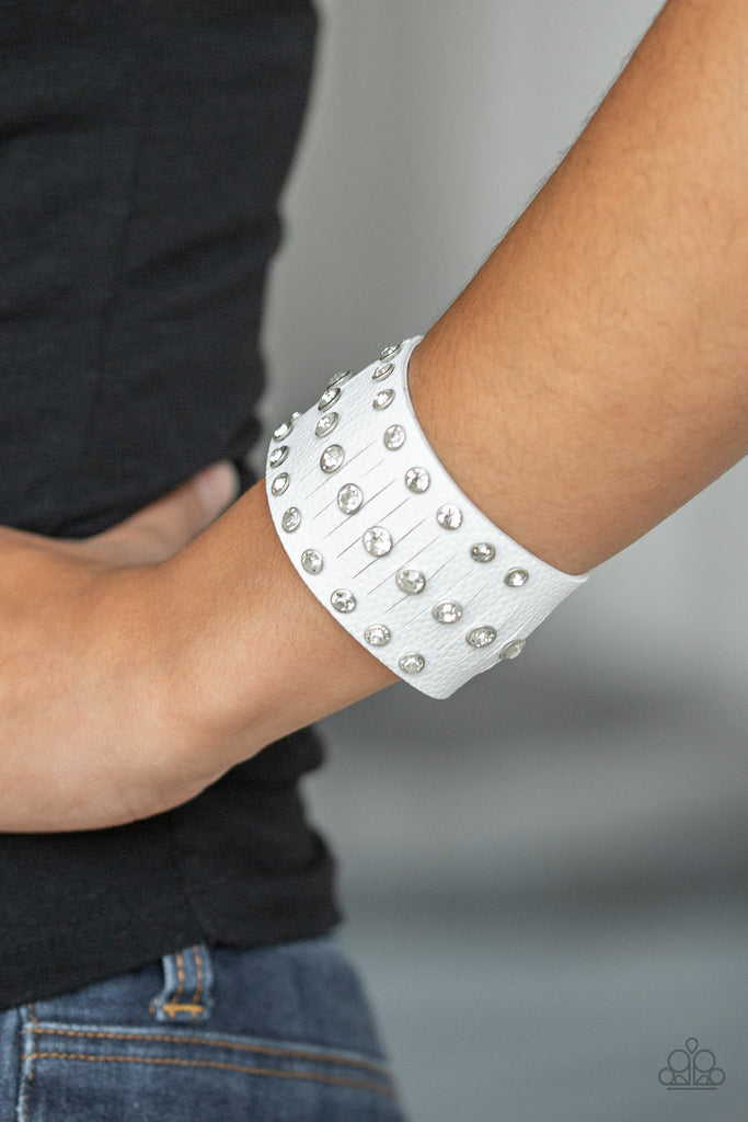 Pressed into sleek silver frames, glittery white rhinestones are studded across a thick white leather band for a sassy finish. Features an adjustable snap closure.    Sold as one individual bracelet.