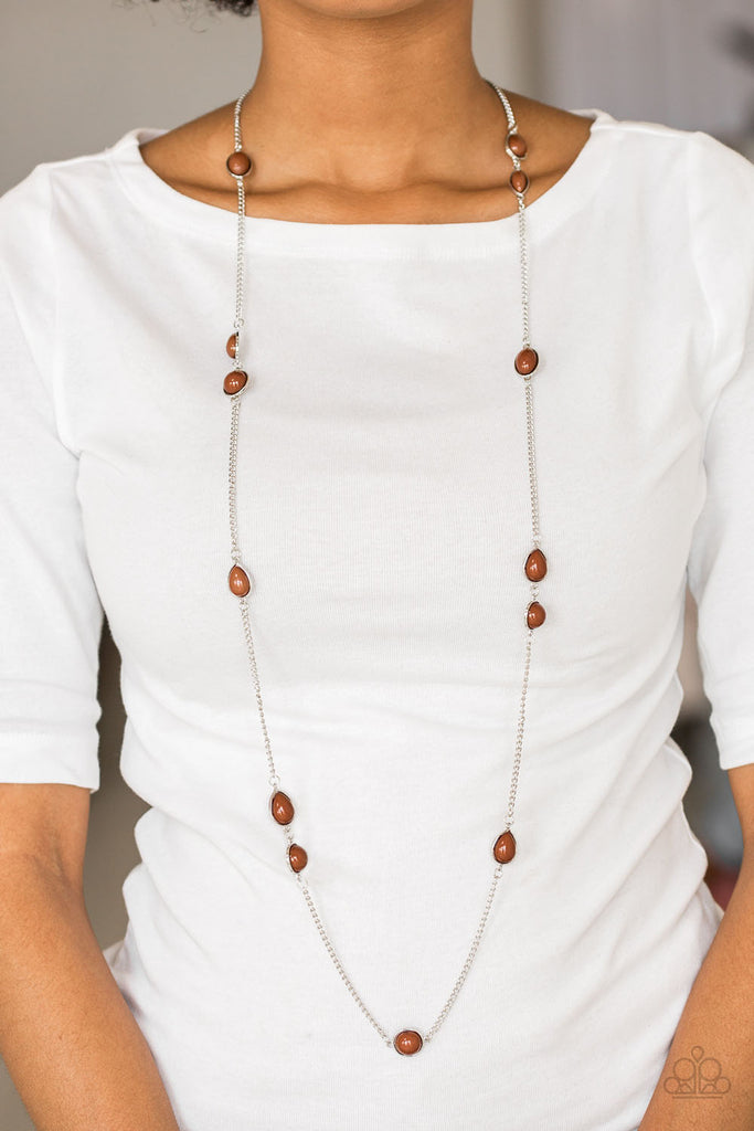 Featuring round and teardrop shapes, brown beading trickles along an elongated silver chain for a seasonal look. Features an adjustable clasp closure.  Sold as one individual necklace. Includes one pair of matching earrings.