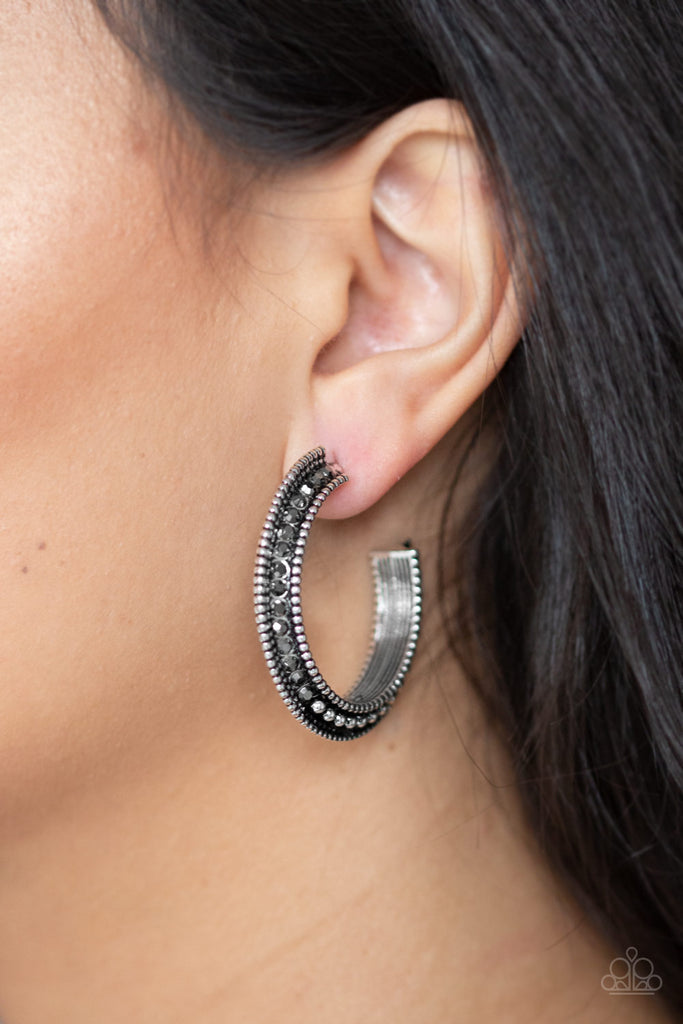 The top half of a bold silver frame is encrusted in hematite rhinestones, giving way to glistening silver studs for an edgy finish. Earring attaches to a standard post fitting. Hoop measures approximately 1 1/4" in diameter.  Sold as one pair of hoop earrings.
