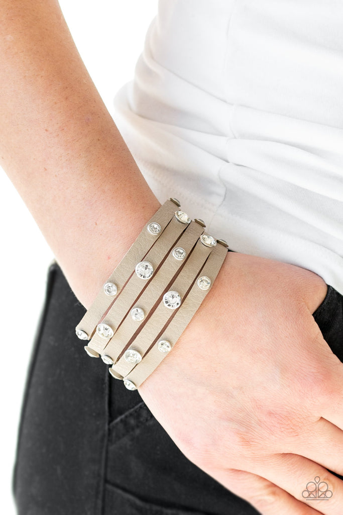 Dotted with glassy white rhinestones, a thick brown leather band has been spliced into five glittery strands around the wrist for a sassy look. Features an adjustable snap closure.  Sold as one individual bracelet.