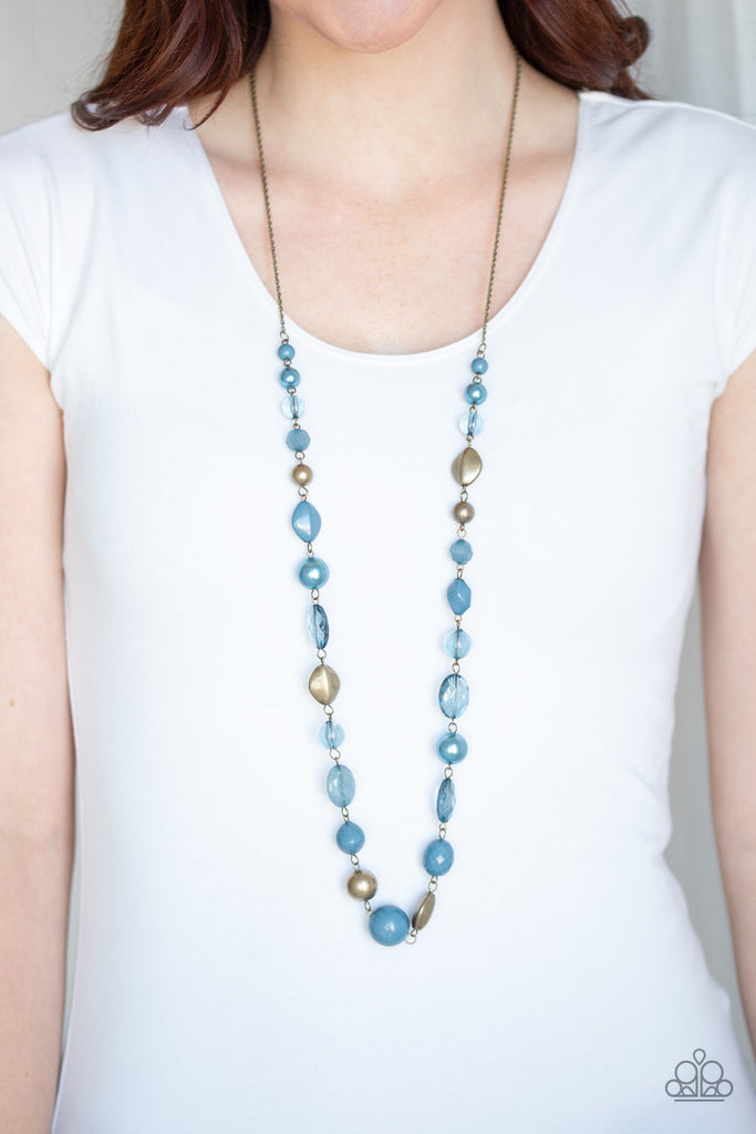 Varying in opacity and shape, a collection of polished, pearly, and glassy blue beads link with antiqued brass beads across the chest for a whimsical finish. Features an adjustable clasp closure.  Sold as one individual necklace. Includes one pair of matching earrings.
