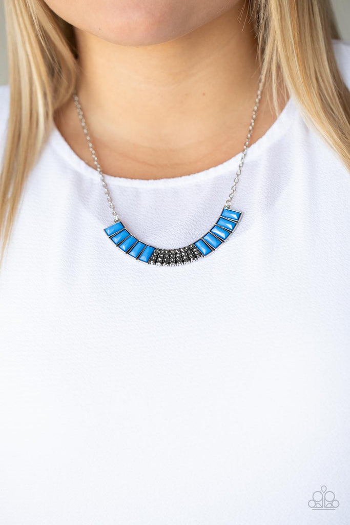 Stacked rows of hematite rhinestones and faceted emerald cut French Blue beads coalesce into a colorful half moon pendant, creating a refreshing pop of color below the collar. Features an adjustable clasp closure.  Sold as one individual necklace. Includes one pair of matching earrings.