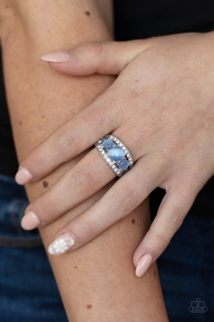 A trio of round Cerulean cat’s eye stones is set in silver pronged fittings between two dainty silver bands that are encrusted in rows of glassy white rhinestones, coalescing into an elegantly layered centerpiece atop the finger. Features a dainty stretchy band for a flexible fit.  Sold as one individual ring.