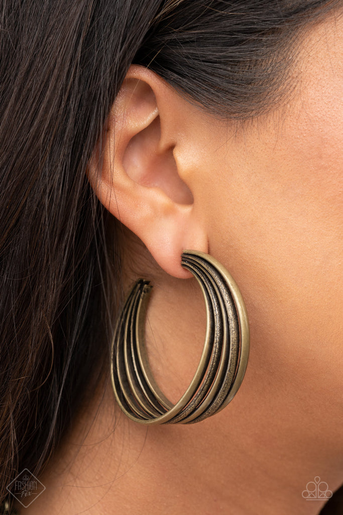 Textured brass rings merge with antiqued matte rings in a curvy ribbon of rustic drama as they wrap around behind the ear. Earring attaches to a standard post fitting. Hoop measures approximately 2" in diameter.  Sold as one pair of hoop earrings.