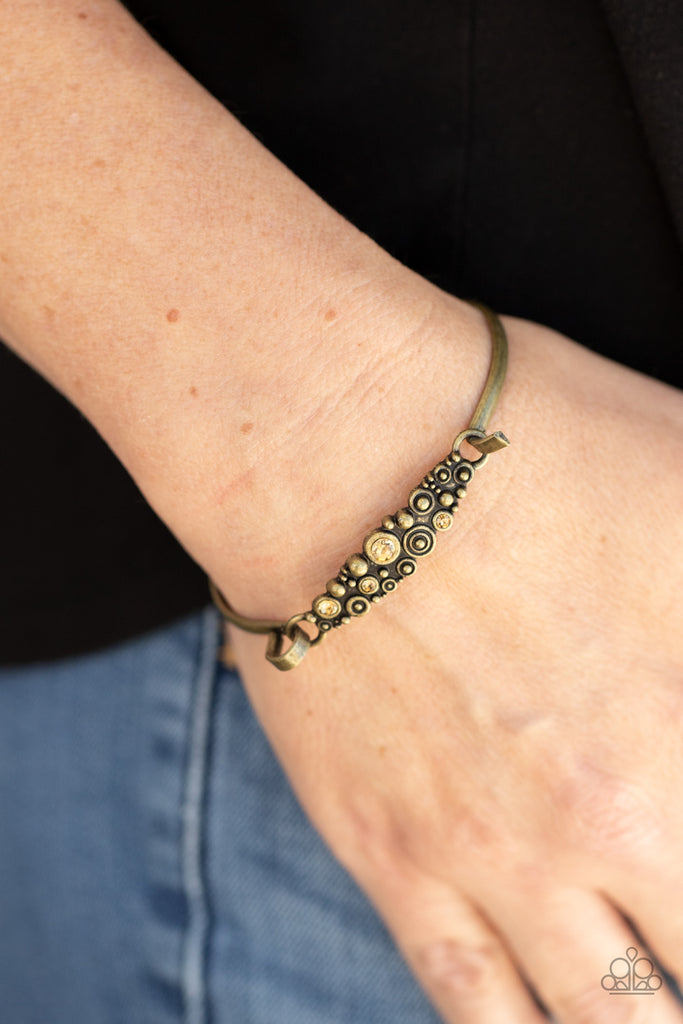 A cluster of engraved and antiqued brass swirls merge with topaz rhinestones and coalesce into a whimsical display across the wrist on a dainty brass cuff. Features a hook and eye closure.  Sold as one individual bracelet.  
