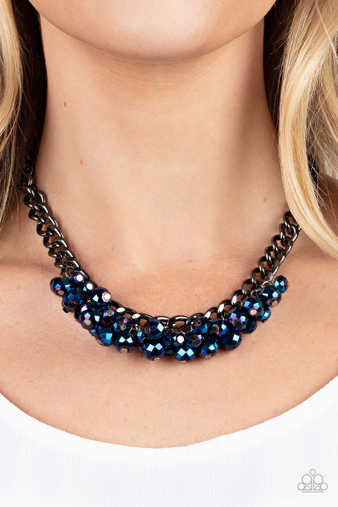 A faceted collection of metallic flecked blue beads cluster along the center of a chunky gunmetal curb chain, creating a stellar fringe below the collar. Features an adjustable clasp closure.  Sold as one individual necklace. Includes one pair of matching earrings.  