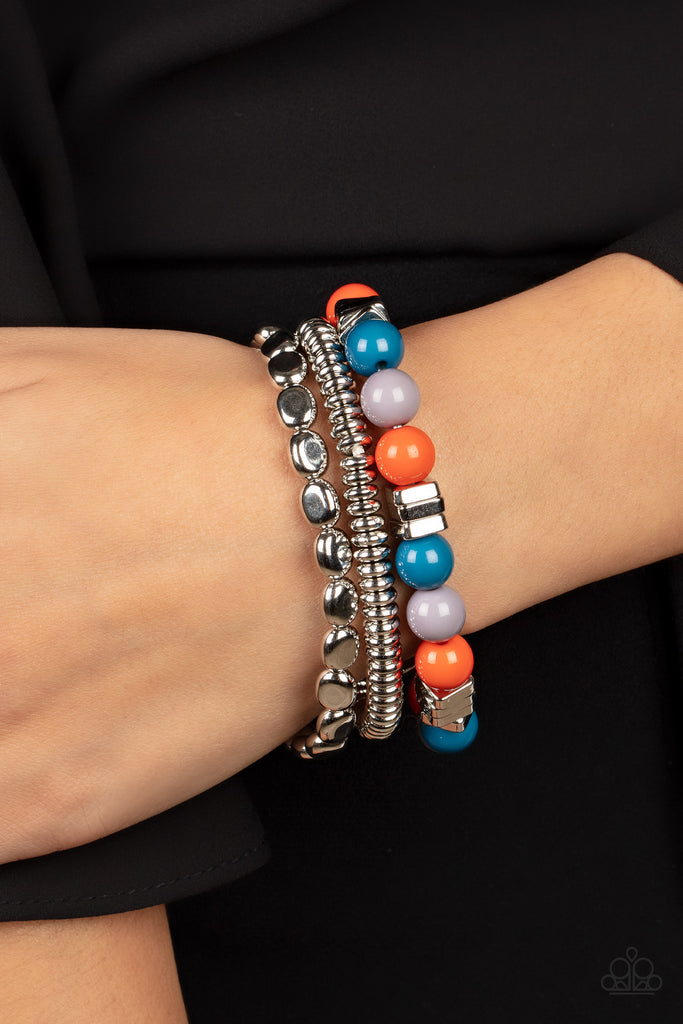 A mismatched collection of silver discs, silver cubes, bubbly multicolored acrylic, and silver pebble-like beads are threaded along stretchy bands around the wrist, creating fiery layers.  Sold as one set of three bracelets.