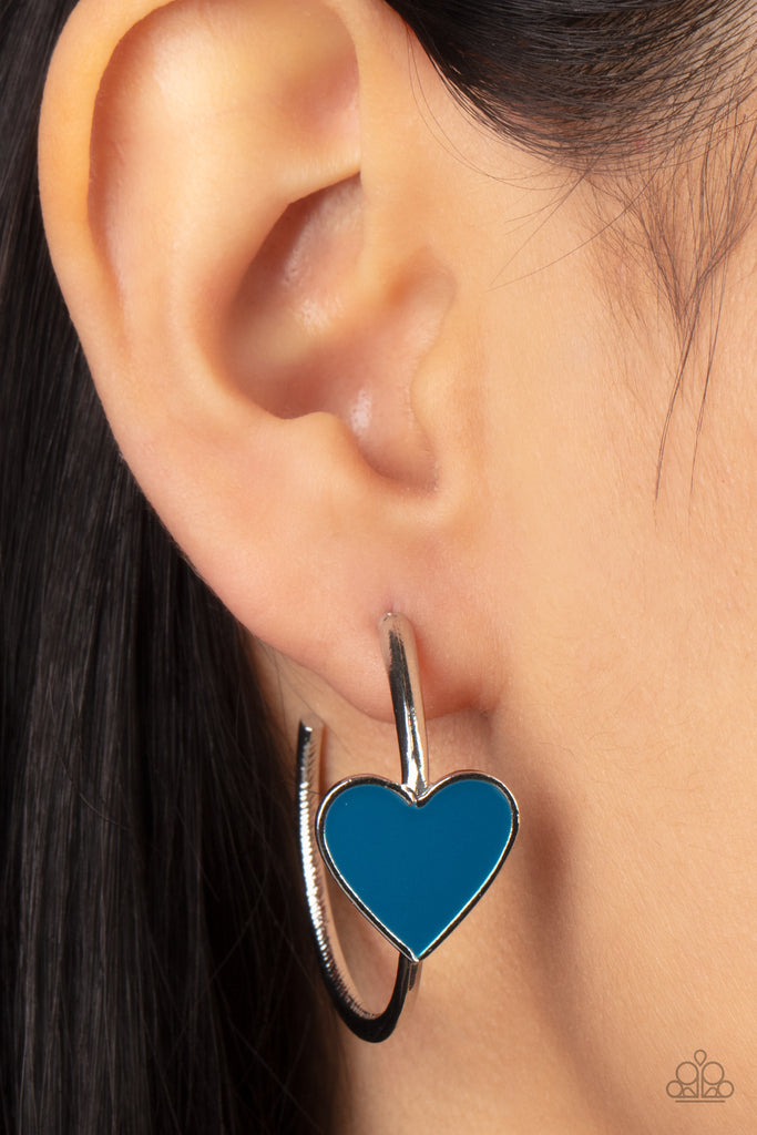 A charming Mykonos Blue heart adorns the front of a classic silver hoop resulting in a whimsical fashion. Earring attaches to a standard post fitting. Hoop measures approximately 1 1/4" in diameter.  Sold as one pair of hoop earrings.