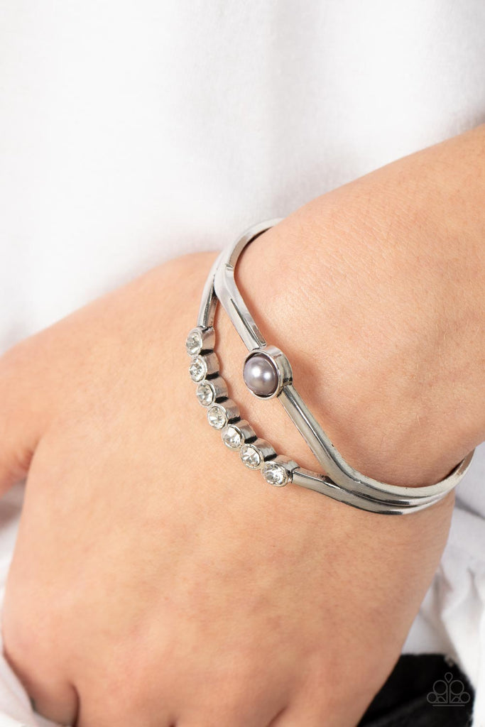 A row of white rhinestones and a solitaire silver pearl adorn the layered center of a classic silver cuff, creating a timeless piece around the wrist.  Sold as one individual bracelet.  