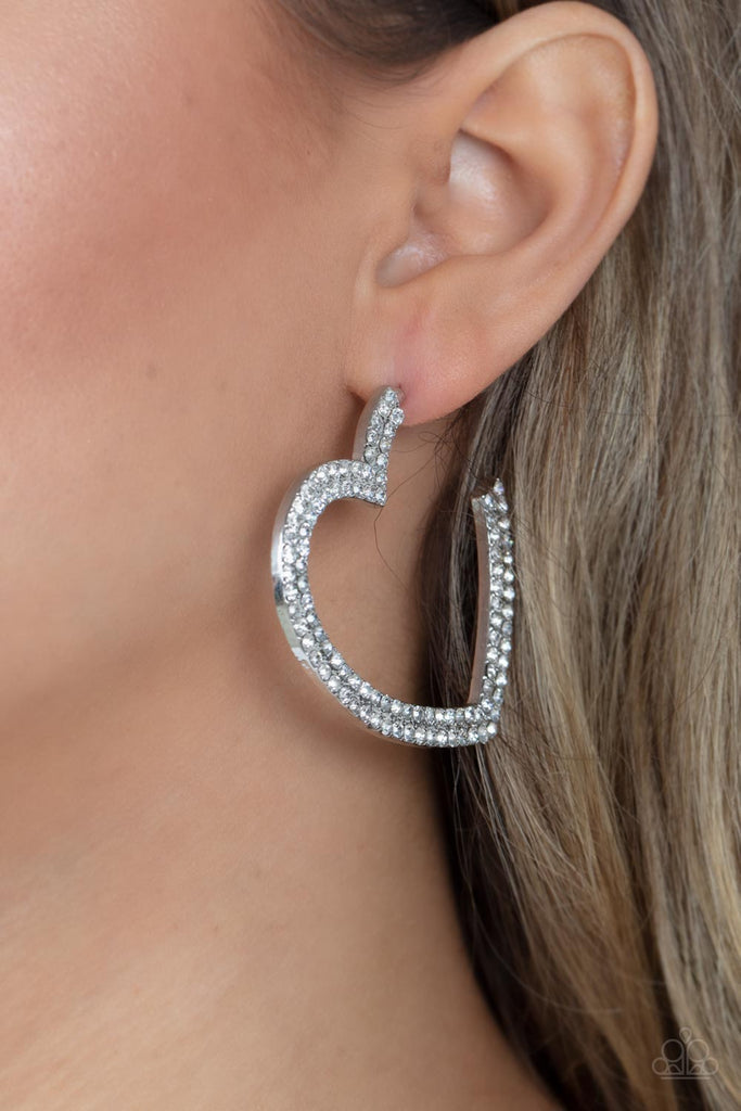 Two rows of blinding white rhinestones are encrusted along the front of a heart shaped silver hoop, creating a heart-stopping sparkle. Hoop measures approximately 2" in diameter. Earring attaches to a standard post fitting.  Sold as one pair of hoop earrings.