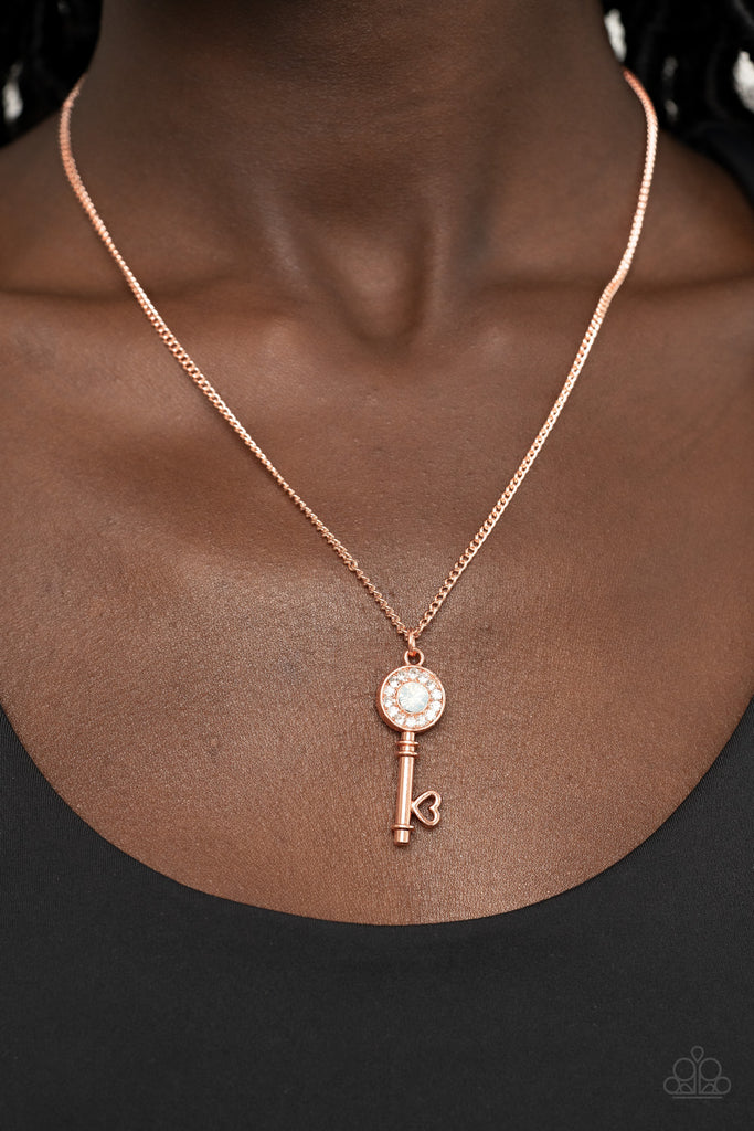 Bordered in glassy white rhinestones, an opal white rhinestone adorns a shiny copper key pendant at the bottom of a dainty shiny copper chain for a whimsical fashion. Features an adjustable clasp closure.  Sold as one individual necklace. Includes one pair of matching earrings.