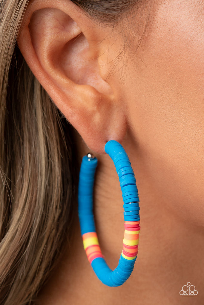 Rubbery blue, pink, yellow, and orange bands are threaded along an oversized silver hoop, creating a courageous pop of color. Earring attaches to a standard post fitting. Hoop measures approximately 2 1/4" in diameter.  Sold as one pair of hoop earrings.