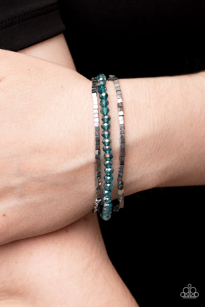 Two rows of dainty silver cube beads and one row of iridescent blue crystal-like beads are threaded along stretchy bands around the wrist, creating stellar layers.  Sold as one set of three bracelets.  
