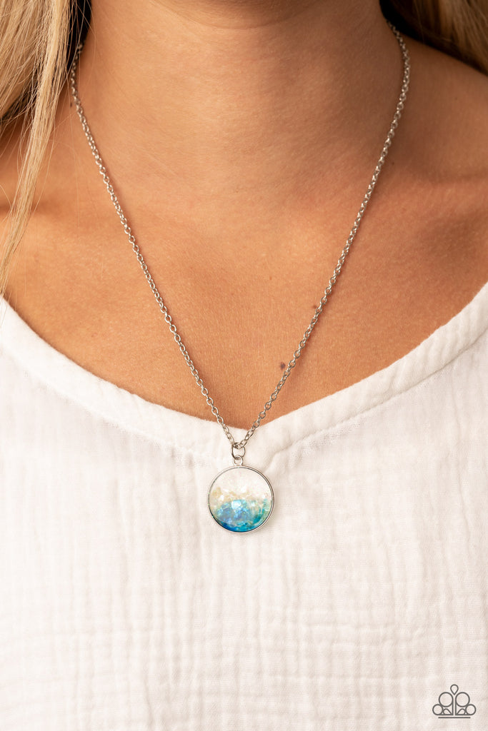 Crushed pieces of iridescent white and blue shell-like accents are encased in a glassy silver fitting at the bottom of a silver chain, resulting in a colorful pop of shimmer below the collar. Features an adjustable clasp closure.  Sold as one individual necklace. Includes one pair of matching earrings.