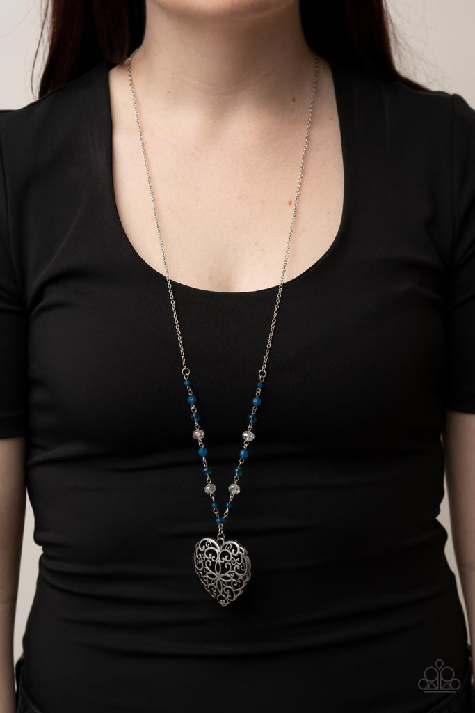 Featuring opaque and glassy crystal-like finishes, a dainty collection of Mykonos Blue and white beads gives way to an oversized filigree filled heart frame, creating an antiqued locket inspired pendant at the bottom of a lengthened silver chain. Features an adjustable clasp closure.  Sold as one individual necklace. Includes one pair of matching earrings.