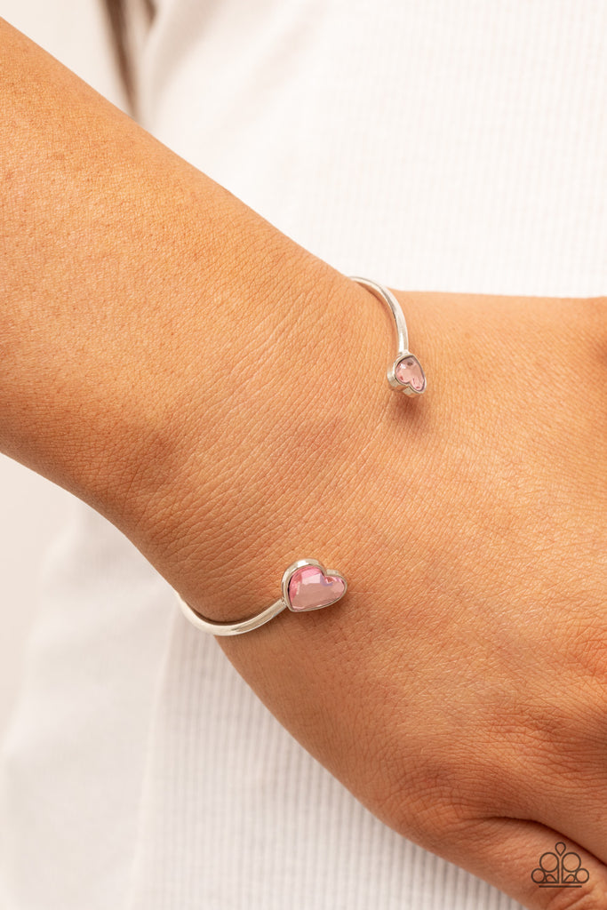 Enhanced with glitzy pink rhinestones, two silver hearts adorn the ends of a silver band that curls around the wrist for a flirtatious open-faced style cuff.  Sold as one individual bracelet.  