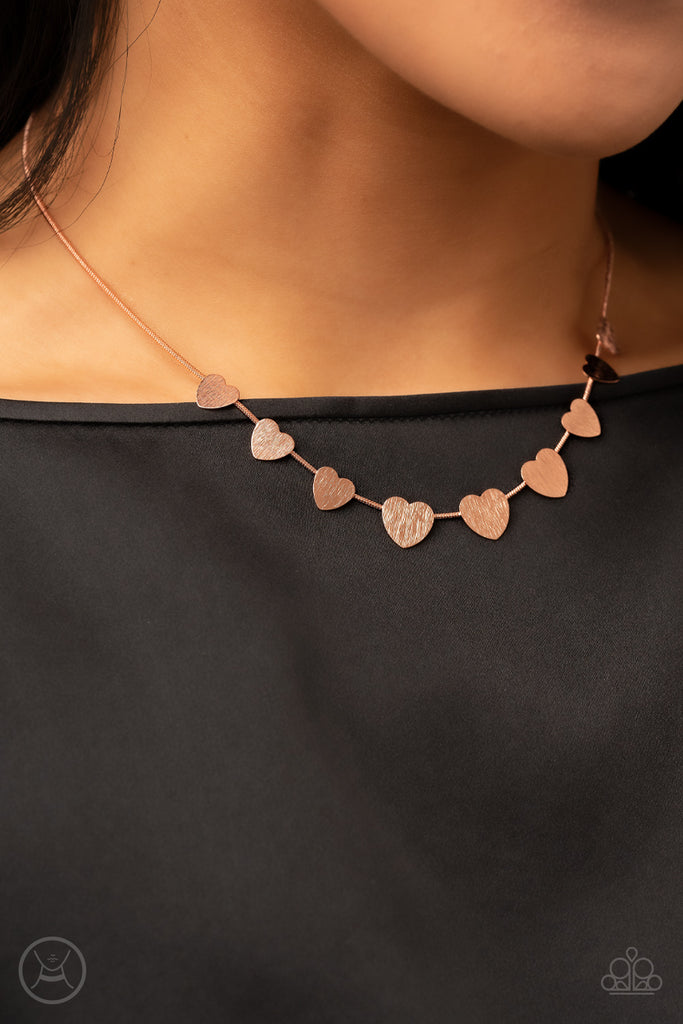 Delicately scratched in shimmer, a dainty collection of flat shiny copper heart frames gradually increases in size along a shiny copper snake chain around the neck for a flirtatious fashion. Features an adjustable clasp closure.  Sold as one individual choker necklace. Includes one pair of matching earrings.