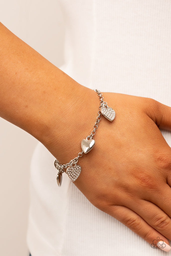 lusty-lockets-white  Shiny silver heart charms delicately alternate with white rhinestone encrusted heart frames along a silver chain around the wrist, resulting in a flirtatious fringe. Features an adjustable clasp closure.  Sold as one individual bracelet.
