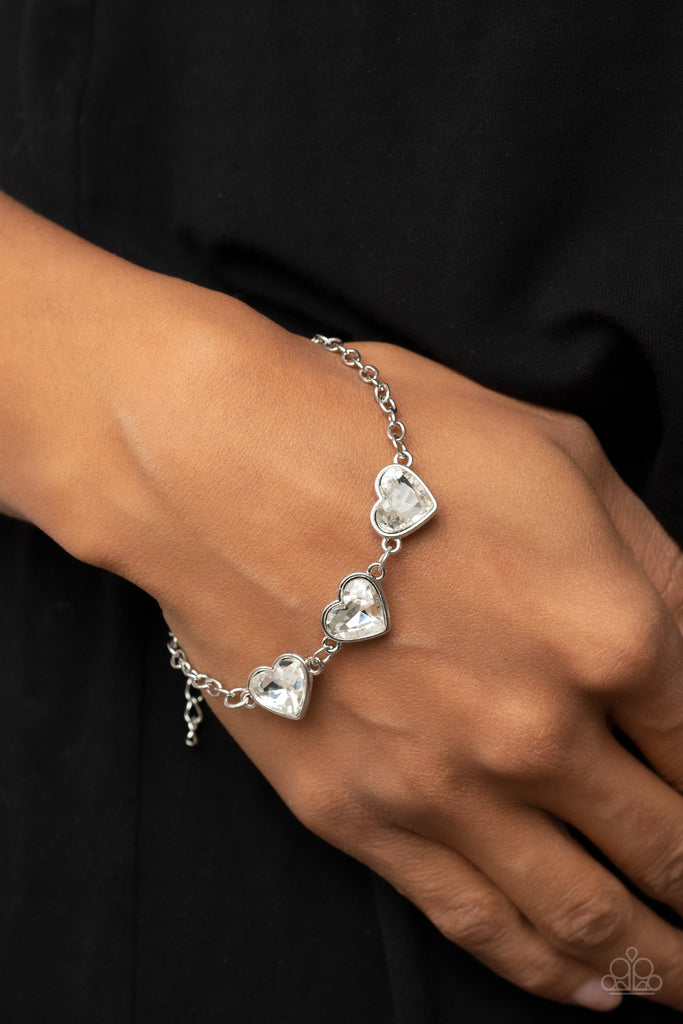 Nestled in silver frames, a trio of glittery white heart-shaped gems delicately links across the wrist for a dash of swoon-worthy shimmer. Features an adjustable clasp closure.  Sold as one individual bracelet.