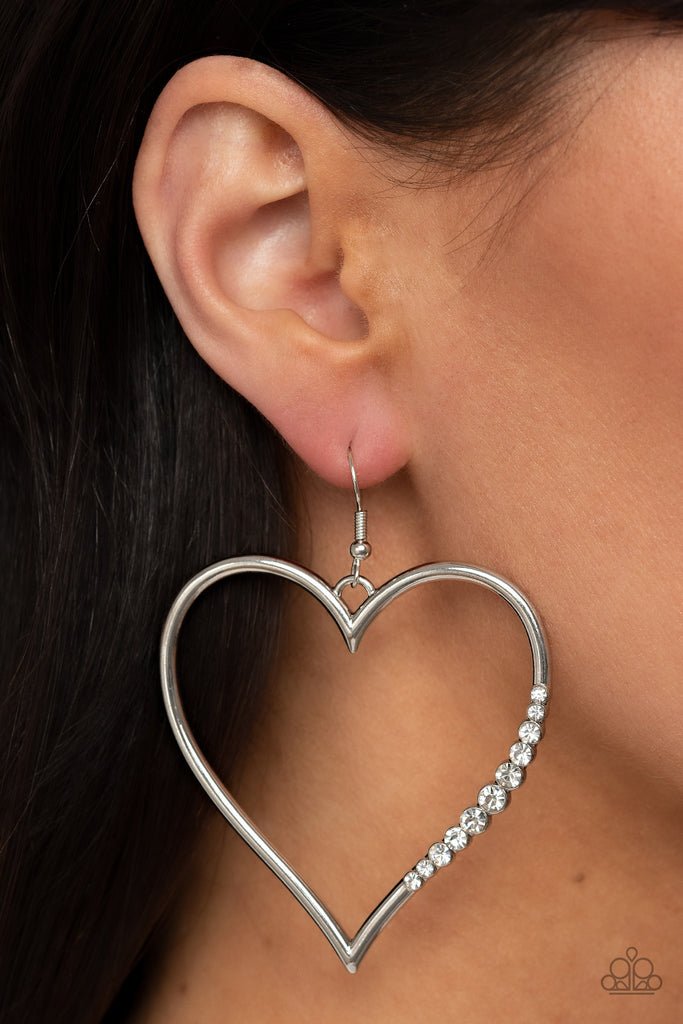 A section of glassy white rhinestones adorns a curvaceous silver heart frame, resulting in a heart-stopping sparkle. Earring attaches to a standard fishhook fitting.  Sold as one pair of earrings.