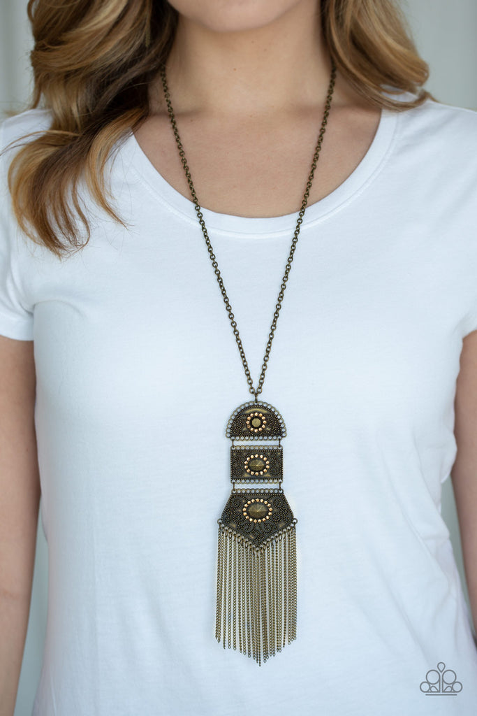 Brass beads encircled by topaz rhinestones are nestled inside a row of three vintage frames that cascade down the chest at the bottom of an elongated brass chain. Glistening brass chains stream from the bottom of the stacked pendant, creating a gorgeously tapered tassel. Features an adjustable clasp closure.  Sold as one individual necklace. Includes one pair of matching earrings.