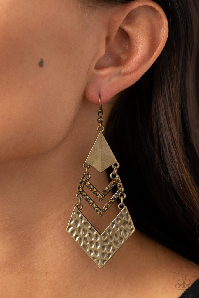 A creased brass kite-shaped frame, aurum rhinestone encrusted chevron-like frame, and hammered brass chevron-like frame link into an edgy lure. Earring attaches to a standard fishhook fitting.  Sold as one pair of earrings.