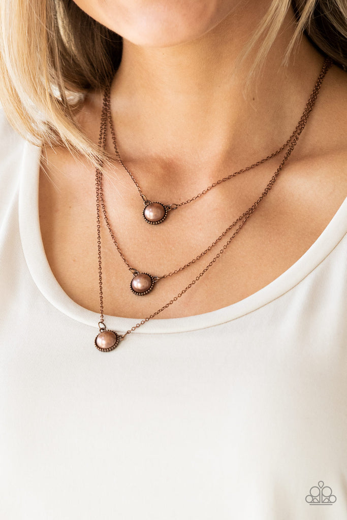 Three copper pearl drop pendants layer down the chest in a refined fashion. Features an adjustable clasp closure.  Sold as one individual necklace. Includes one pair of matching earrings.