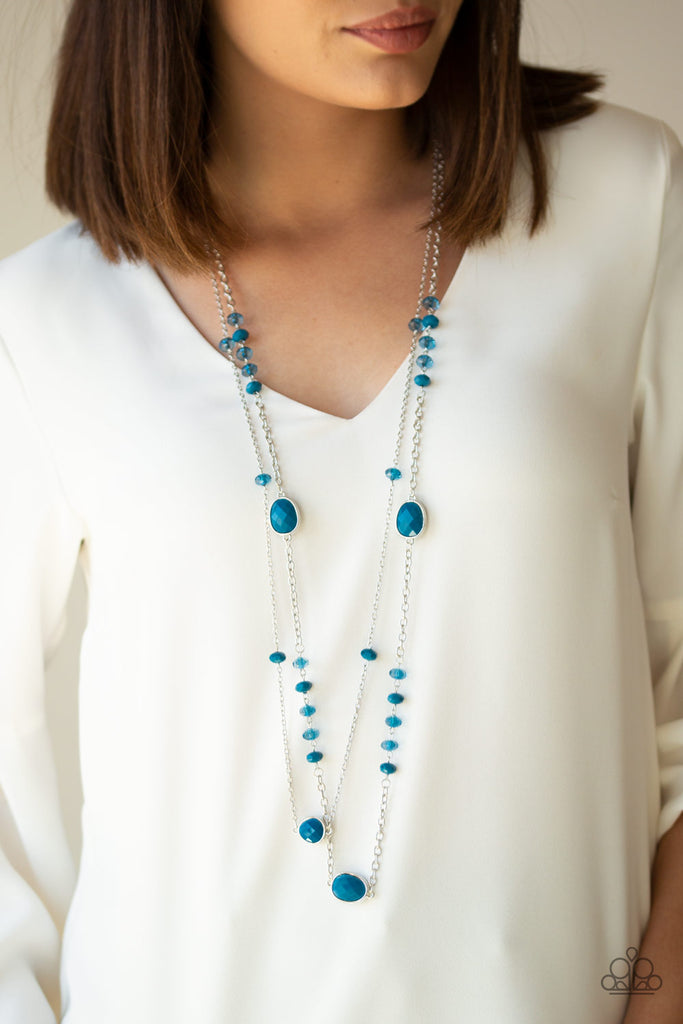 A collection of polished, glassy, and oversized blue beads trickle along two shimmery silver chains down the chest, creating colorfully refined layers. Features an adjustable clasp closure.  Sold as one individual necklace. Includes one pair of matching earrings.