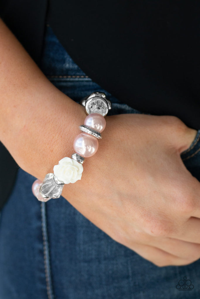 A collection of silver, pearly pink, and white crystal-like beads are threaded along a stretchy band around the wrist. A shiny white resin rose joins the refined palette for a glamorous finish.  Sold as one individual bracelet.