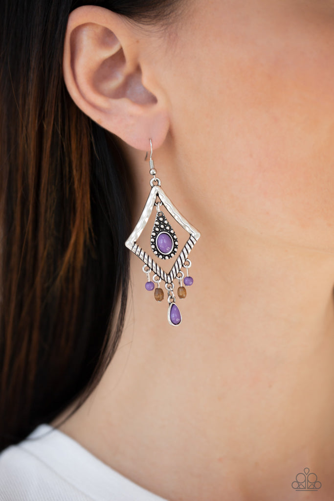 Featuring a vivacious purple bead, a studded silver teardrop swings from the top of a kite-shaped silver frame. Dainty red and wooden accents swing from the bottom of a hammered frame, creating a seasonal fringe. Earring attaches to a standard fishhook fitting.  Sold as one pair of earrings.