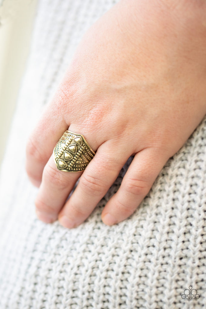 Dainty triangular frames are pressed down the center of a shimmery brass frame radiating with studded textures for a tribal inspired look. Features a stretchy band for a flexible fit.  Sold as one individual ring.
