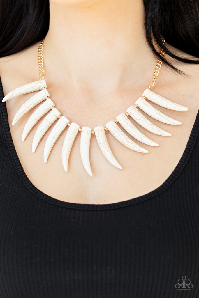 Infused with dainty gold beads, tusk-shaped white stone beads are threaded along an invisible wire below the collar, creating a wild fringe. Features an adjustable clasp closure.  Sold as one individual necklace. Includes one pair of matching earrings.  