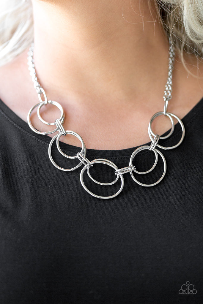 Doubled silver hoops link below the collar for a bold industrial look. Features an adjustable clasp closure. Sold as one individual necklace. Includes one pair of matching earrings.