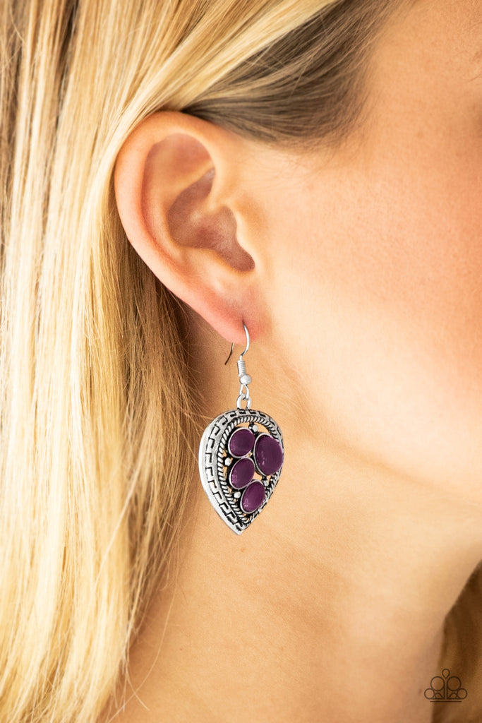 Varying in size, polished purple beads are sprinkled across the center of an asymmetrical heart-shaped frame for a whimsical look. Earring attaches to a standard fishhook fitting.  Sold as one pair of earrings.