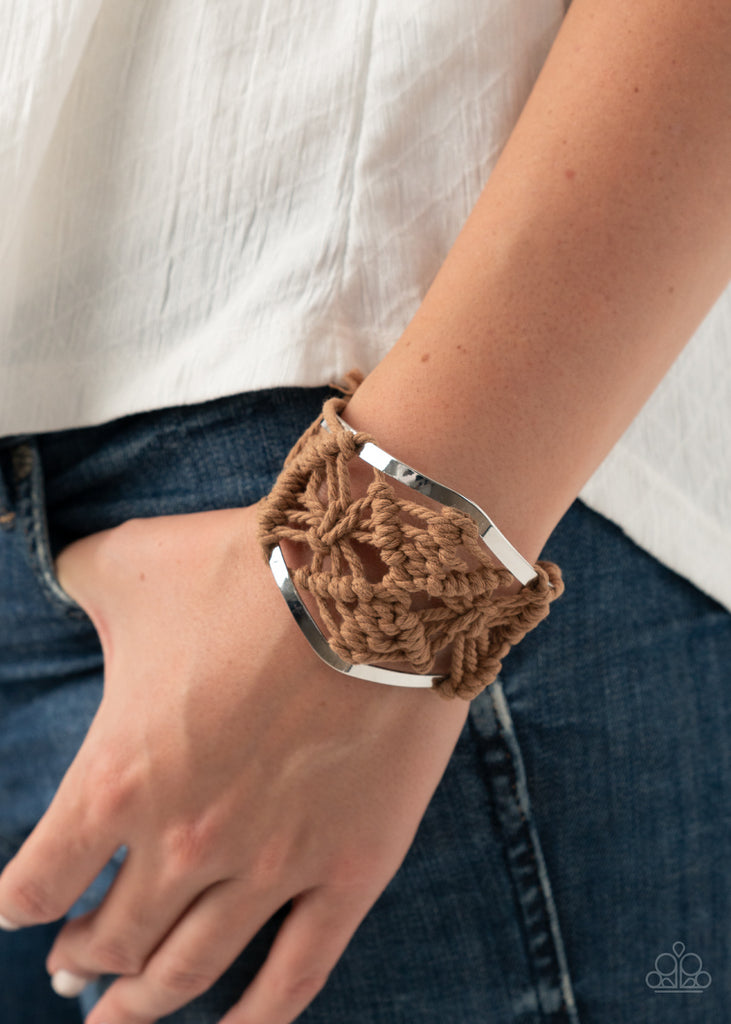 Brown cording decoratively knots and weaves around an airy silver cuff for a macramé inspired look. Knotted around the ends, brown tassels flair out from bottoms of the cuff for a wanderlust finish. Sold as one individual bracelet.