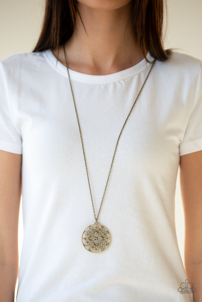 Featuring a whimsical mandala pattern, a glistening brass pendant swings from the bottom of a lengthened brass chain for a seasonal look. Features an adjustable clasp closure.  Sold as one individual necklace. Includes one pair of matching earrings.