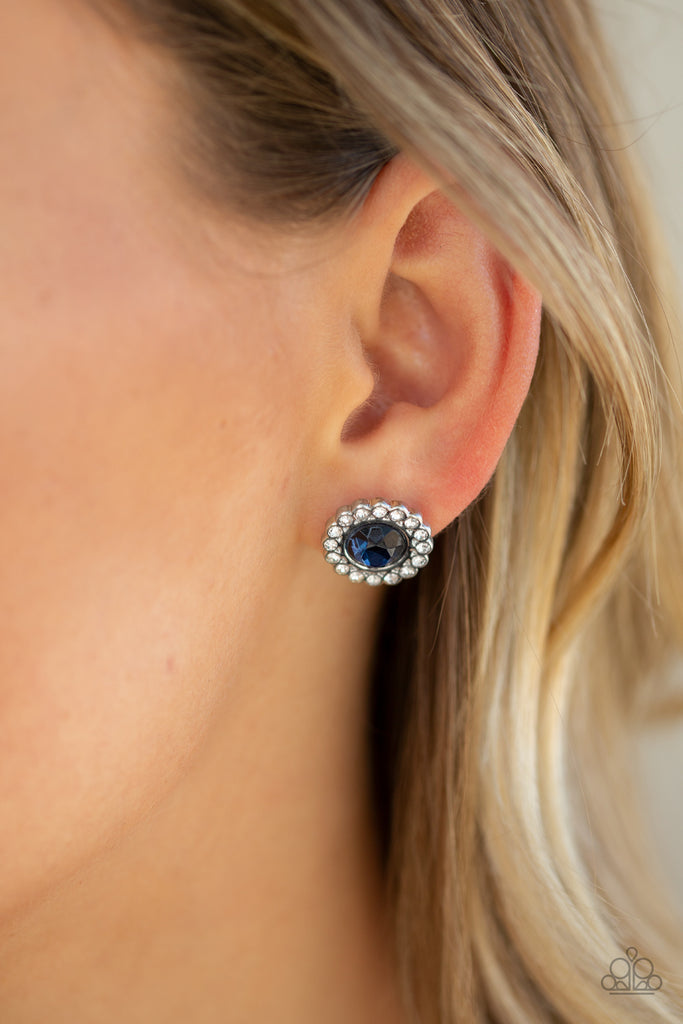 A glittery ring of dainty white rhinestones spins around a blue rhinestone center, creating a sparkling floral frame. Earring attaches to a standard post fitting.  Sold as one pair of post earrings.