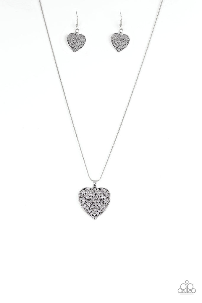 Filled with vine-like filigree detail, a silver heart pendant swings below the collar for a vintage inspired look. Features an adjustable clasp closure.  Sold as one individual necklace. Includes one pair of matching earrings.
