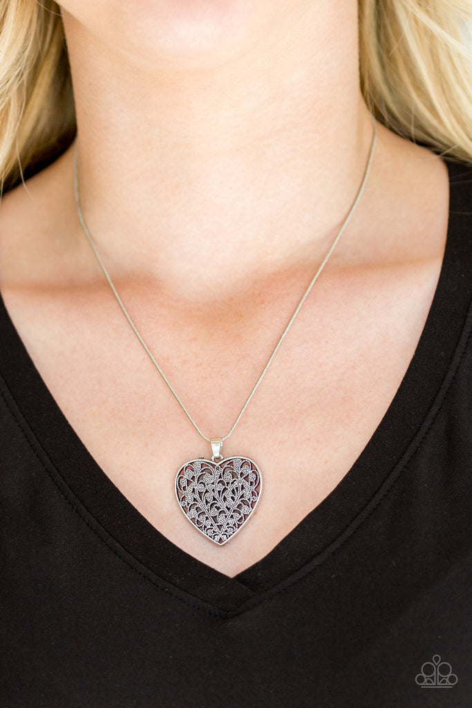 Filled with vine-like filigree detail, a silver heart pendant swings below the collar for a vintage inspired look. Features an adjustable clasp closure.  Sold as one individual necklace. Includes one pair of matching earrings.