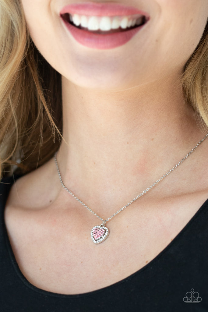 Encrusted in sparkly pink rhinestones, a stacked heart frame swings from a dainty silver chain below the collar for a romantic look. Features an adjustable clasp closure.Sold as one individual necklace. Includes one pair of matching earrings.