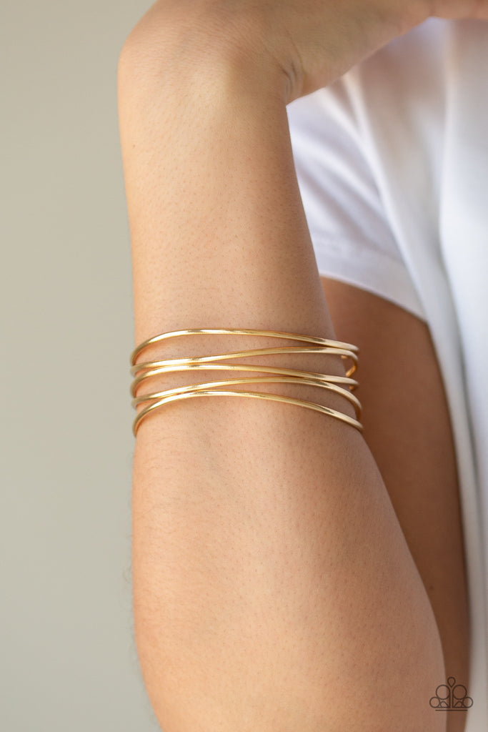 A collection of glistening gold bangles join into an abstractly layered cuff around the wrist for a casual glam.  Sold as one individual bracelet.