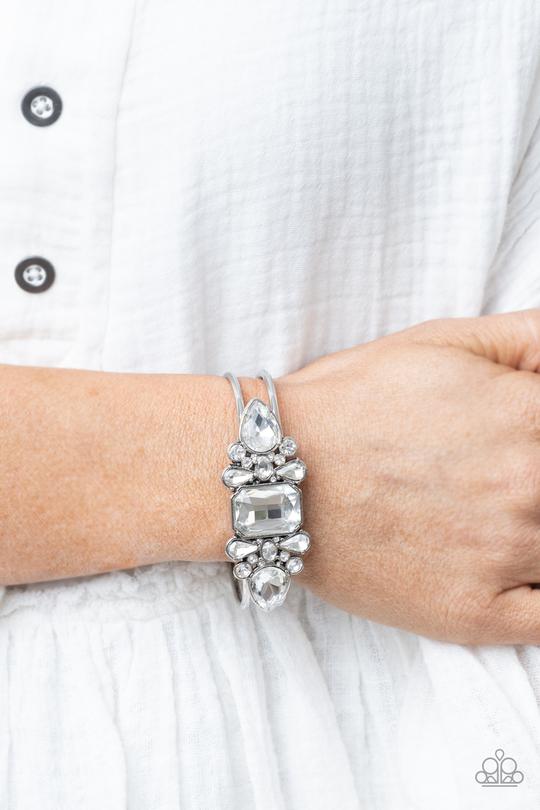 A blinding collection of round and marquise-cut white rhinestones are encrusted across the front of a shiny silver bar, curling around the wrist to create a timeless cuff-like bangle. Features a hinged closure.  ﻿Sold as one individual bracelet