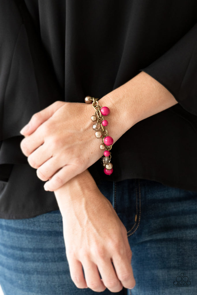 Pearly brass, polished pink, and glittery crystal-like beads swing from a bold brass chain, creating a refined fringe around the wrist. Features an adjustable clasp closure.  Sold as one individual bracelet.