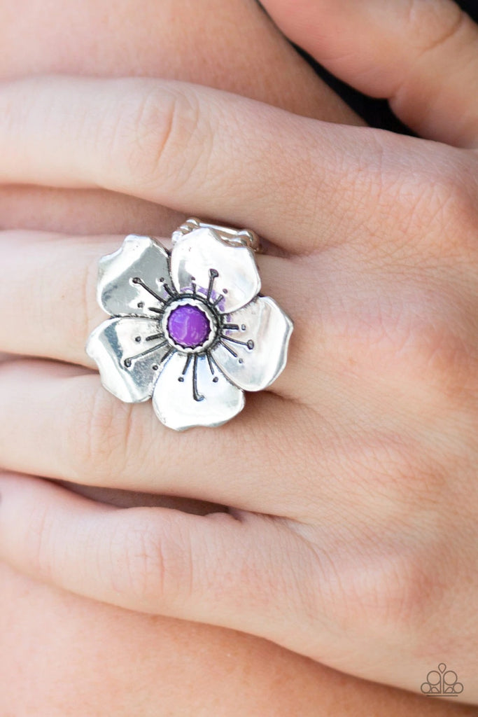 A bright purple bead is pressed into the center of a blooming silver flower radiating with antiqued details for a whimsical look. Features a stretchy band for a flexible fit.  Sold as one individual ring.